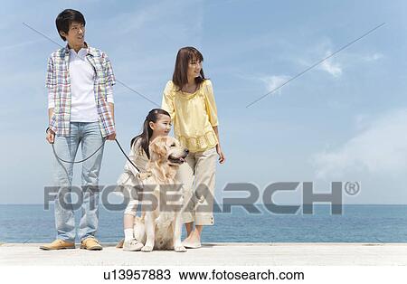 Stock Image - Family of Three and Dog on Beach. Fotosearch