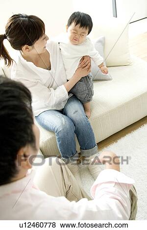 Family of three in living room View Large Photo Image Stock Photo - Family of three in living room. Fotosearch
