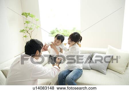 Family of three in living room View Large Photo Image Stock Photo - Family of three in living room. Fotosearch