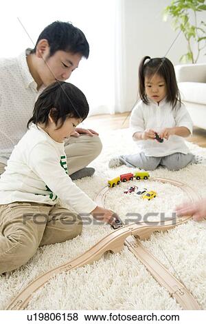 Stock Photo - Family playing in living room with toy train. Fotosearch