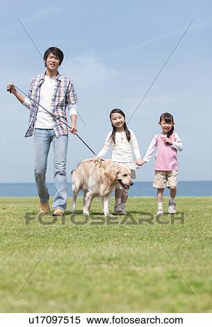 Stock Photography - Father and Two Daughters Walking the Dog. Fotosearch
