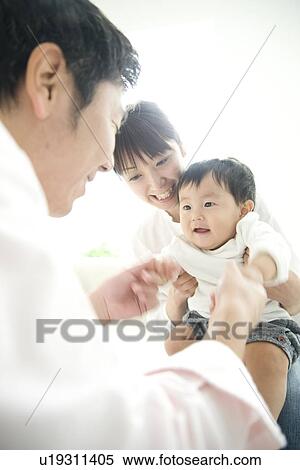 Stock Photography - Father holding son's hands, son sitting on mother's lap. Fotosearch