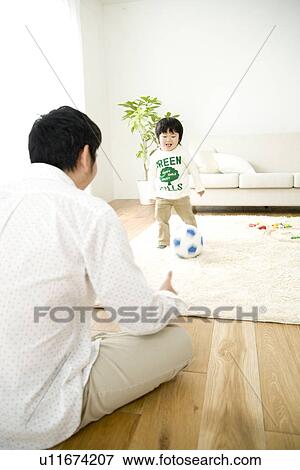 Stock Photo - Father watching son playing with soccer ball. Fotosearch