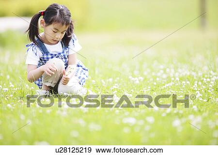 Stock Photo - Girl Sitting on Grass Surrounded By Flowers. Fotosearch