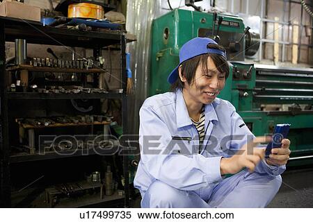 Stock Photography - Male Worker Using Phone In Factory. Fotosearch