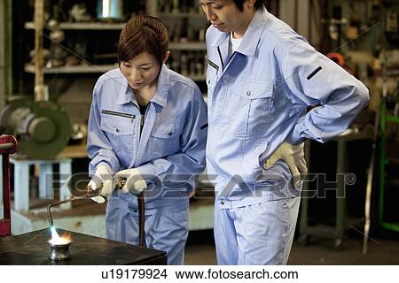 Picture - Man and Woman Welding In Factory. Fotosearch
