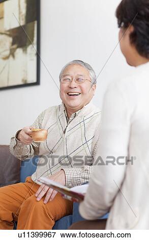 Stock Photo - Mature Couple In Living Room With Coffee. Fotosearch
