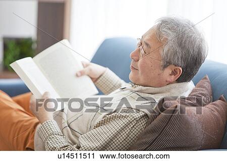 Stock Image - Mature Man Reading In Living Room. Fotosearch