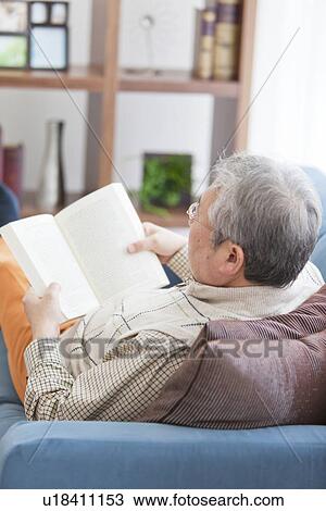 Stock Image - Mature Man Reading In Living Room. Fotosearch
