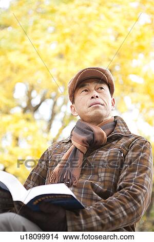 Picture - Mature Man Reading In Park In Autumn. Fotosearch
