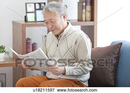 Stock Photo - Mature Man Reading Paper In Living Room. Fotosearch