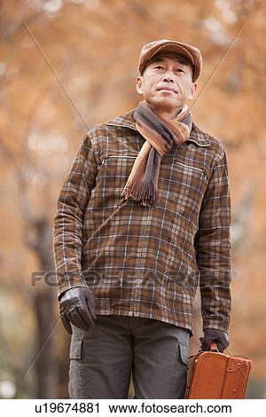 Stock Image - Mature Man Walking In the Woods In Autumn. Fotosearch