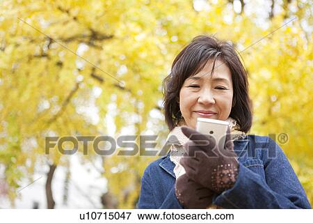 Mature Woman Using Mobile Phone Outdoors In Autumn View Large Photo Image Stock Photo - Mature Woman Using Mobile Phone Outdoors In Autumn. Fotosearch