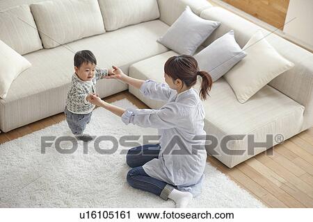 Mother and baby boy playing in living room View Large Photo Image Stock Image - Mother and baby boy playing in living room. Fotosearch