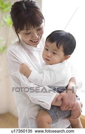 Mother and baby hugging in living room View Large Photo Image Stock Photography - Mother and baby hugging in living room. Fotosearch