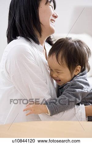 Stock Image - Mother and baby in living room. Fotosearch