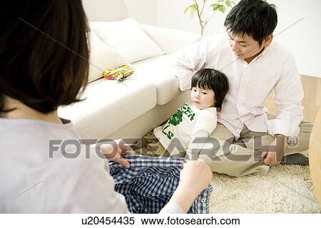 Stock Photography - Mother and father helping son to change clothes. Fotosearch