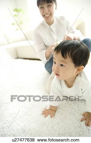 Stock Photo - Mother watching son crawling. Fotosearch