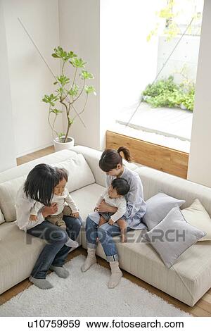 Mothers and their two children sitting on sofa View Large Photo Image Stock Photo - Mothers and their two children sitting on sofa. Fotosearch