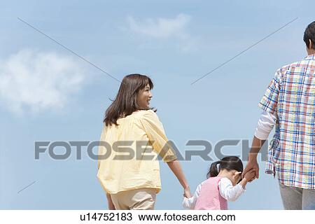 Stock Image - Parents and Daughter Walking Hand In Hand. Fotosearch