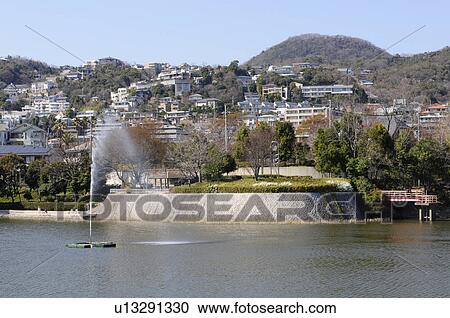 Stock Image - Pond and houses on a hill. Fotosearch
