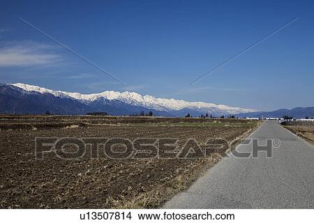 Snowcapped mountain chain behind rural landscape View Large Photo Image Picture - Snowcapped mountain chain behind rural landscape. Fotosearch