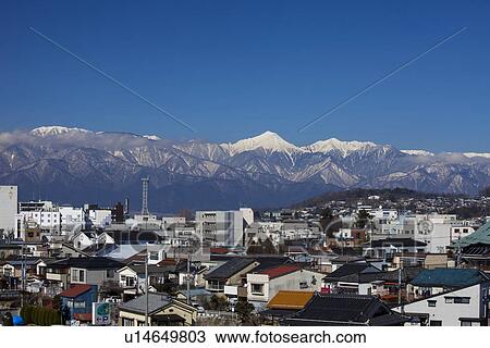Stock Image - Snowcapped mountain chain behind cityscape. Fotosearch