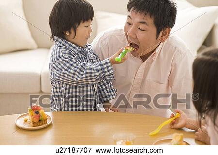 Stock Photo - Son feeding cake to father. Fotosearch