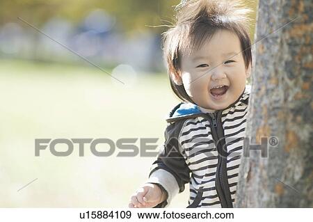 Toddler hiding behind tree View Large Photo Image Stock Photo - Toddler hiding behind tree. Fotosearch