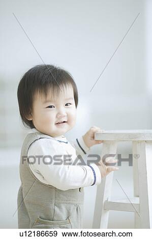 Stock Photo - Toddler standing and holding on to a stool. Fotosearch
