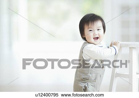 Toddler standing and holding onto a stool View Large Photo Image Stock Photography - Toddler standing and holding onto a stool. Fotosearch
