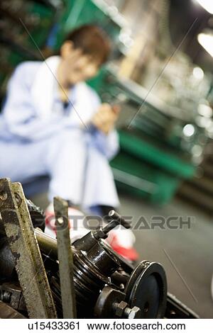 Stock Image - Tools In Foreground, Female Factory Worker In Background. Fotosearch
