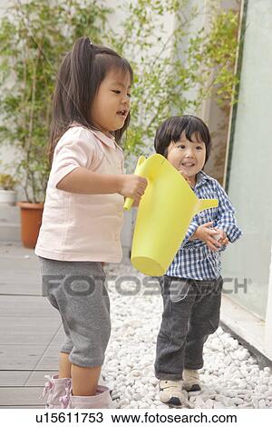 Stock Image - Two children with watering cans. Fotosearch