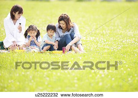 Stock Image - Two Mothers and Two Kids Having Picnic. Fotosearch
