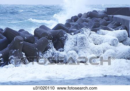 Stock Image - Waves Splashing Against Water Breakers. Fotosearch