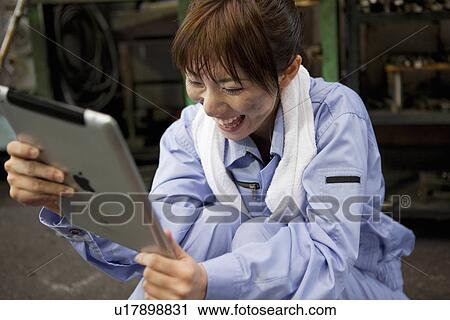 Stock Image - Young Female Worker Using Digital Tablet. Fotosearch