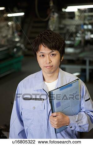 Stock Image - Young Male Factory Worker Holding Files. Fotosearch