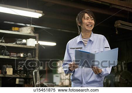 Stock Photography - Young Male Factory Worker With File. Fotosearch