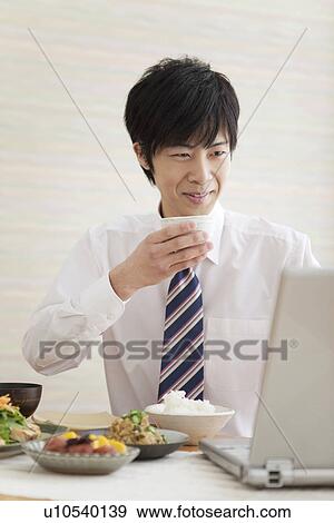 Young Man Having Breakfast and Using Laptop View Large Photo Image Stock Photo - Young Man Having Breakfast and Using Laptop. Fotosearch