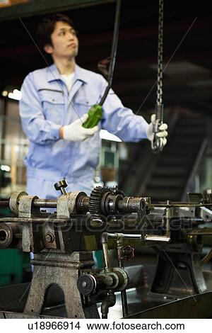 Picture - Young Man Using Machine In Factory. Fotosearch