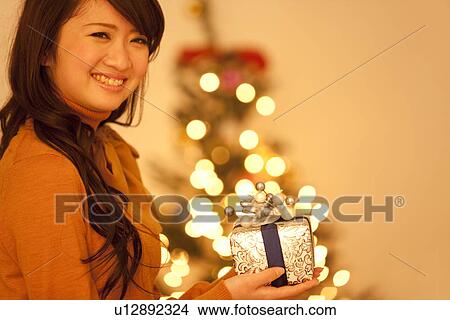 Young Woman Holding Christmas Present View Large Photo Image Picture - Young Woman Holding Christmas Present. Fotosearch