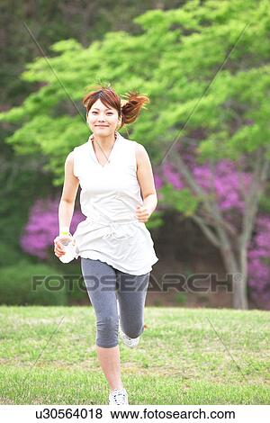 Young Woman Jogging Through Spring Trees in Blossom View Large Photo Image Stock Photo - Young Woman Jogging Through Spring Trees in Blossom. Fotosearch