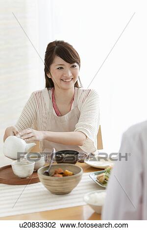 Stock Image - Young Woman Pouring Tea. Fotosearch