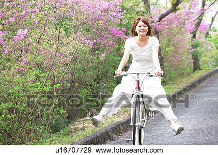 Young Woman Riding On A Bicycle Downhill Through Spring Trees in Blossom View Large Photo Image Stock Photo - Young Woman Riding On A Bicycle Downhill Through Spring Trees in Blossom. Fotosearch