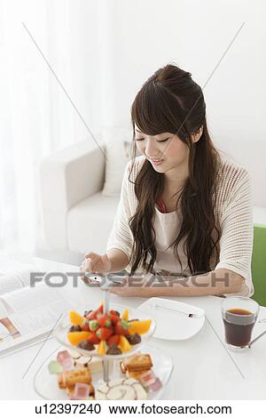 Stock Image - Young Woman Texting at Table. Fotosearch