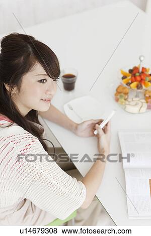 Stock Photo - Young Woman Texting at Table. Fotosearch