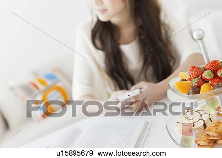 Stock Photo - Young Woman Texting at Table. Fotosearch