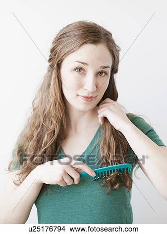 Picture - Attractive young woman combing hair. Fotosearch