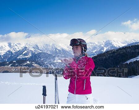 Stock Image - Austria, Maria Alm, Woman at top of mountain blowing snow. Fotosearch