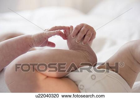 Stock Image - Baby boy (2-5) touching foot. Fotosearch